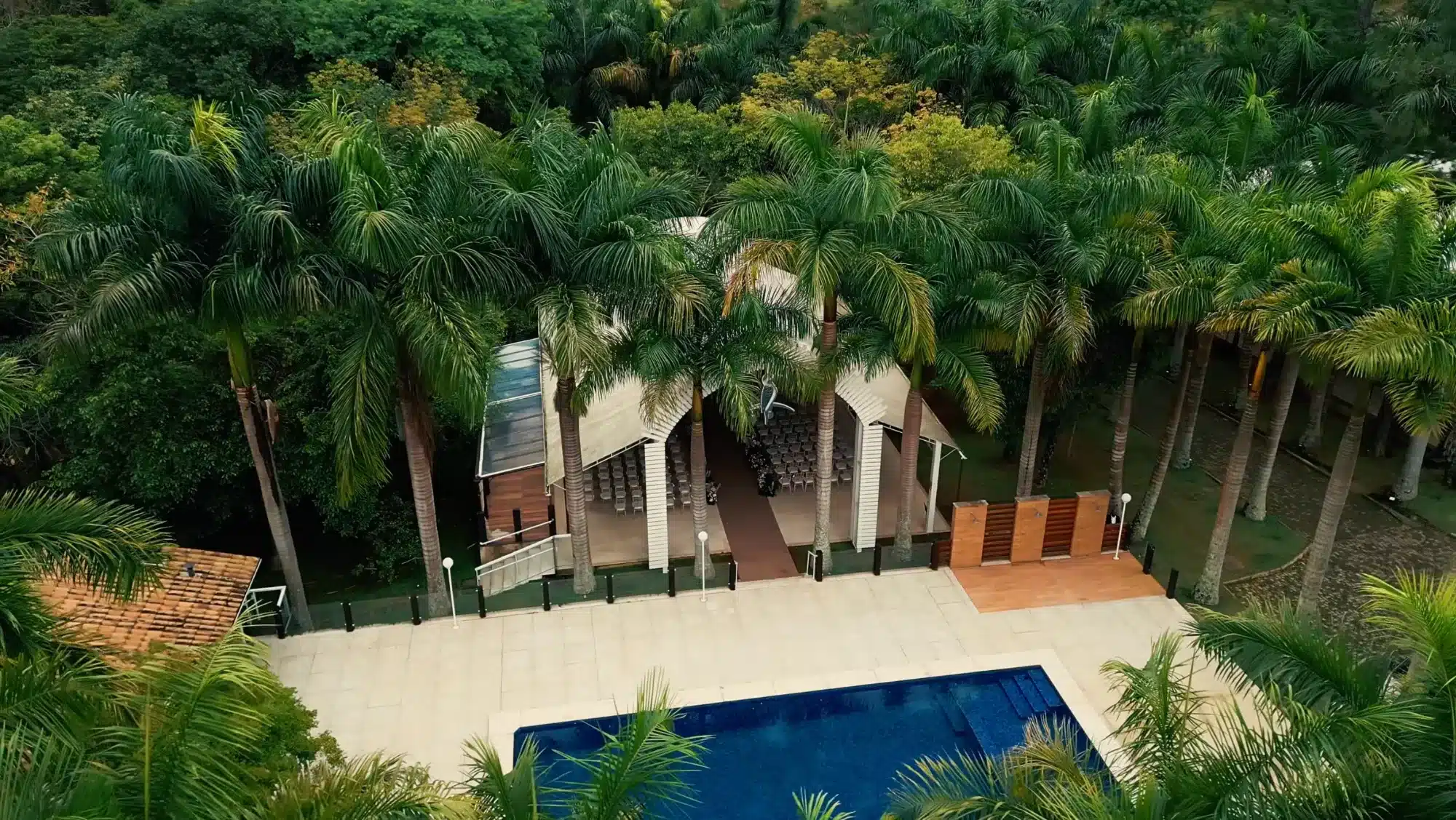 Ambiente coberto da cerimônia de casamento no Fontabella, em Juiz de Fora, vista de drone, entre palmeiras e ao lado da piscina